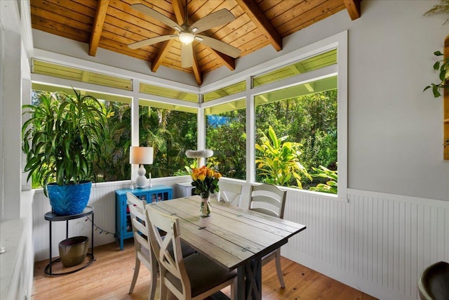 sunroom featuring lofted ceiling with beams, wooden ceiling, a wooden deck, and ceiling fan