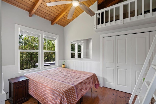 bedroom with a wainscoted wall, vaulted ceiling with beams, wood ceiling, and wood finished floors
