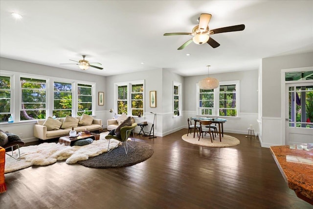 living room with dark wood finished floors, ceiling fan, and a wainscoted wall