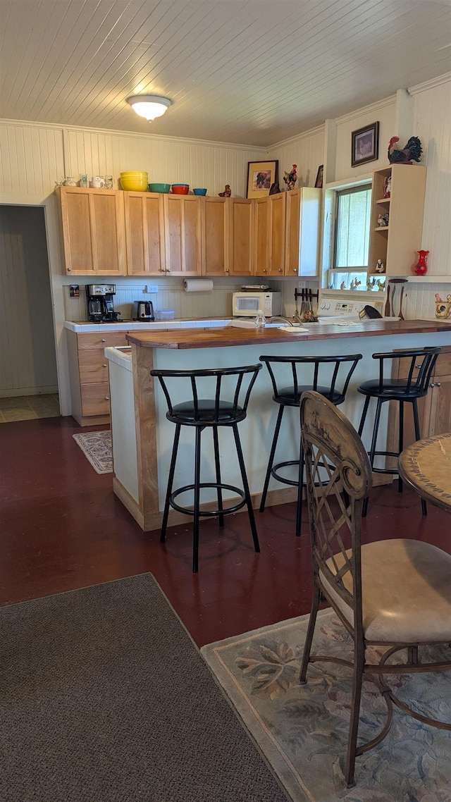 kitchen with wooden ceiling, light countertops, a breakfast bar, white microwave, and decorative backsplash