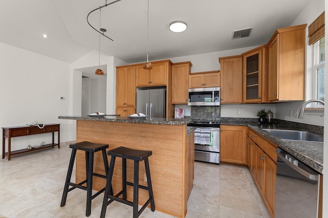 kitchen featuring a kitchen bar, sink, decorative light fixtures, a center island, and appliances with stainless steel finishes