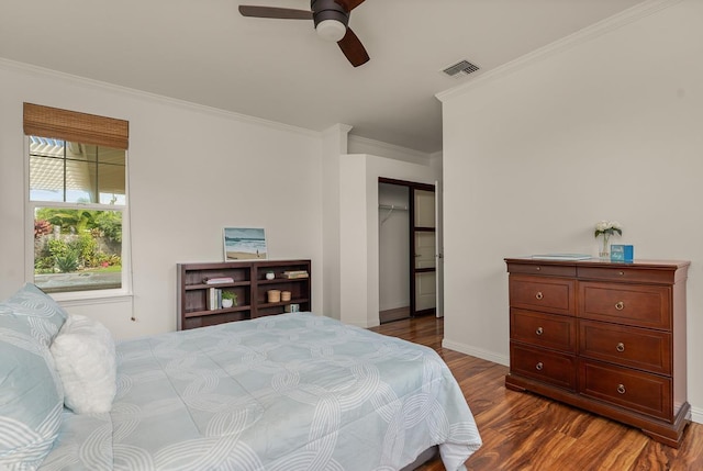 bedroom featuring crown molding, dark wood-type flooring, and ceiling fan