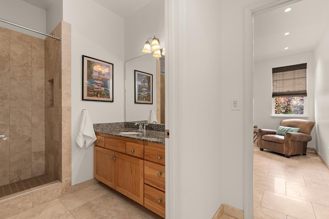 bathroom featuring tiled shower, vanity, and tile patterned flooring