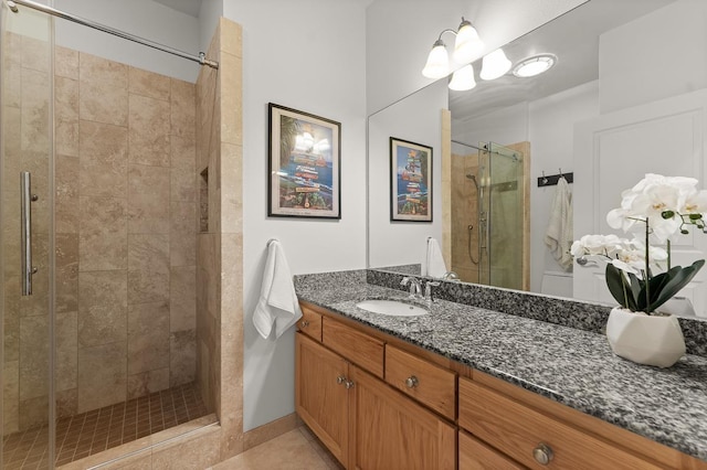 bathroom with a shower with door, vanity, and tile patterned flooring