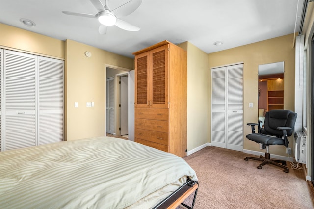 carpeted bedroom with ceiling fan and multiple closets