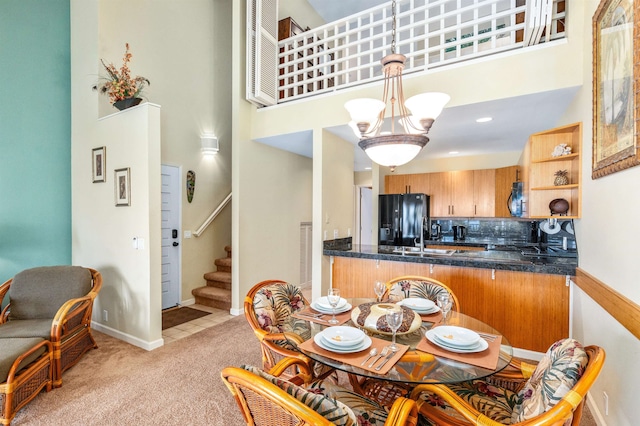 carpeted dining space with a chandelier and a high ceiling