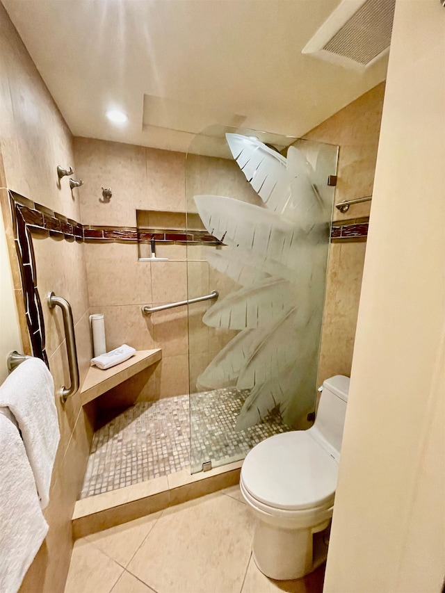 bathroom featuring toilet, tile patterned flooring, and a tile shower