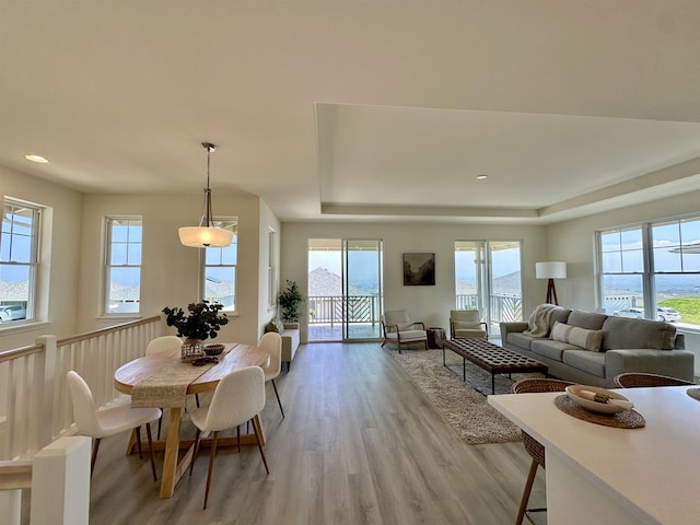 dining area with recessed lighting, a raised ceiling, and light wood finished floors