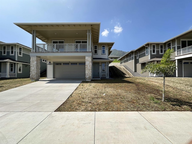 view of front of home featuring driveway, a balcony, a garage, and stone siding