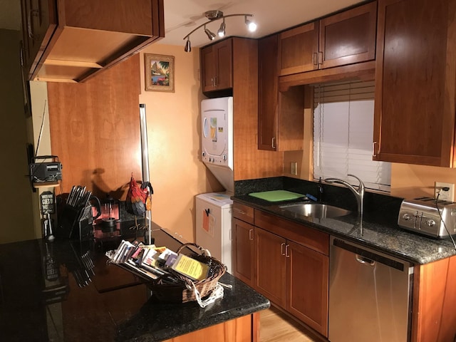 kitchen featuring sink, dishwasher, stacked washer and dryer, and dark stone counters