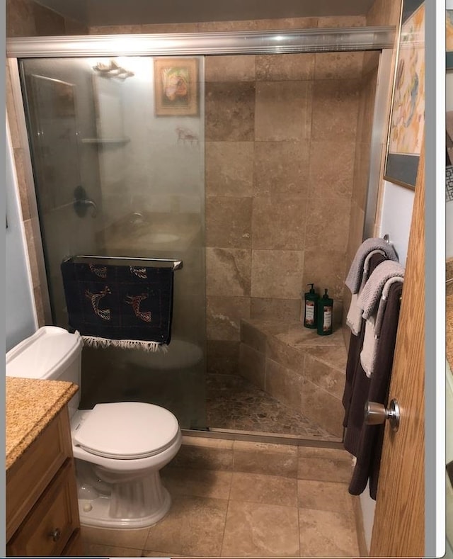 bathroom with a shower with door, vanity, and toilet