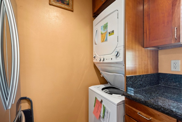 laundry room with cabinets and stacked washer and clothes dryer