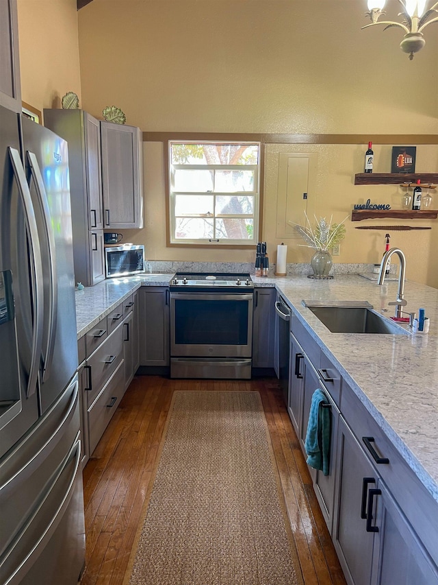 kitchen featuring appliances with stainless steel finishes, light stone counters, sink, gray cabinets, and dark hardwood / wood-style floors