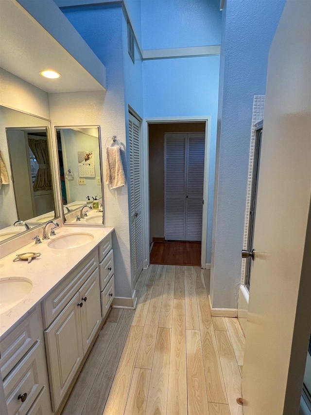 bathroom featuring hardwood / wood-style floors, vanity, and enclosed tub / shower combo