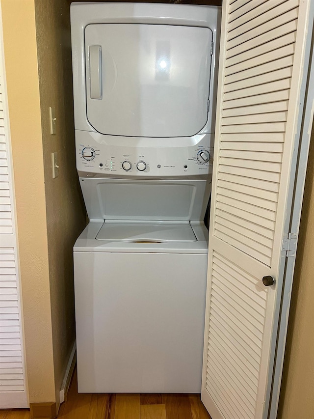 laundry area with hardwood / wood-style floors and stacked washer and dryer