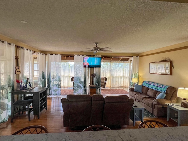 living room featuring hardwood / wood-style flooring, ceiling fan, and a textured ceiling