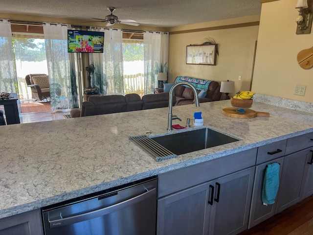 kitchen with dark wood-type flooring, sink, stainless steel dishwasher, ceiling fan, and a textured ceiling