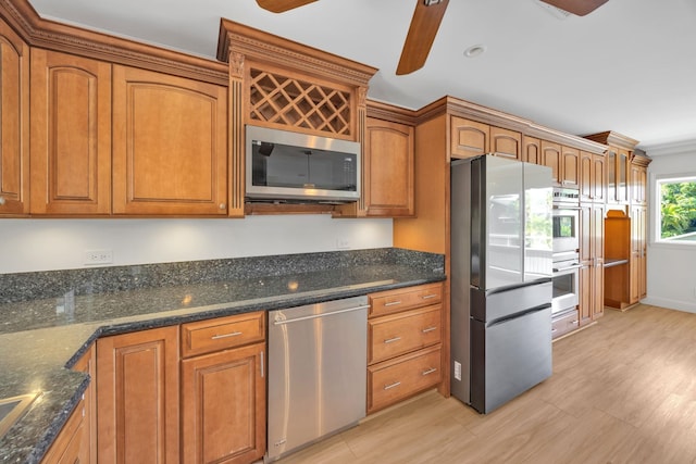 kitchen with ceiling fan, stainless steel appliances, dark stone counters, and light hardwood / wood-style flooring