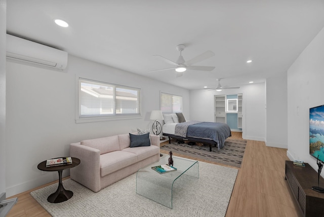 bedroom featuring a wall mounted air conditioner, ceiling fan, and light hardwood / wood-style floors