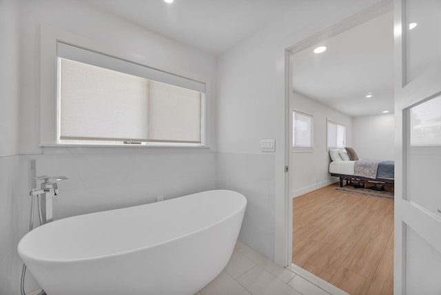 bathroom with a bath, tile walls, and hardwood / wood-style flooring