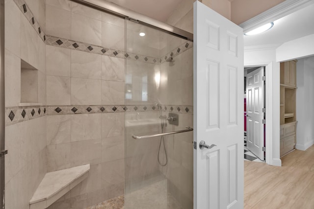 bathroom featuring hardwood / wood-style flooring, crown molding, and walk in shower