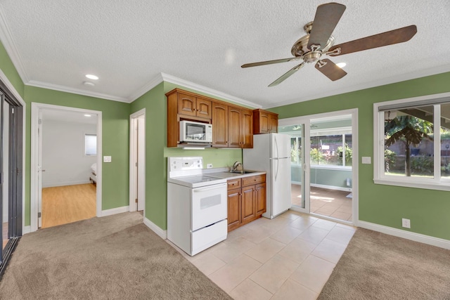 kitchen with light carpet, white appliances, ceiling fan, crown molding, and sink