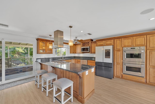 kitchen with island exhaust hood, stainless steel appliances, crown molding, decorative light fixtures, and a kitchen island