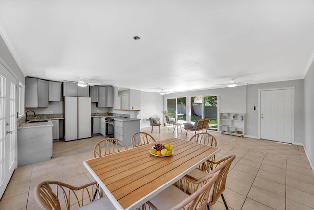 tiled dining area featuring ceiling fan, sink, and crown molding