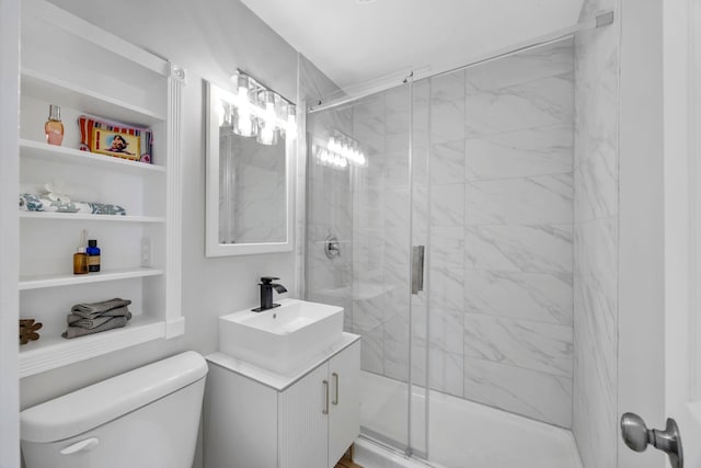 bathroom featuring built in shelves, toilet, a shower with shower door, and vanity