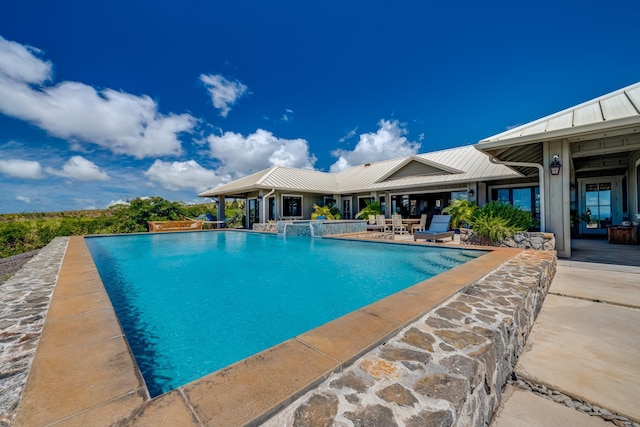 view of swimming pool with pool water feature and a patio