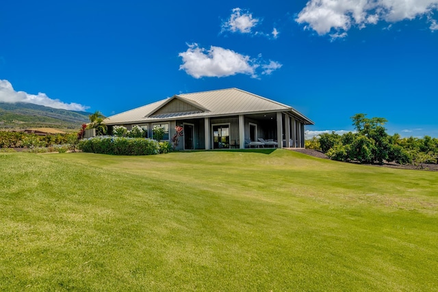 rear view of house featuring a mountain view and a yard