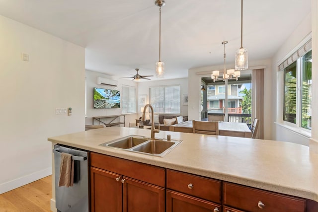 kitchen with decorative light fixtures, a sink, light countertops, stainless steel dishwasher, and a wall mounted AC