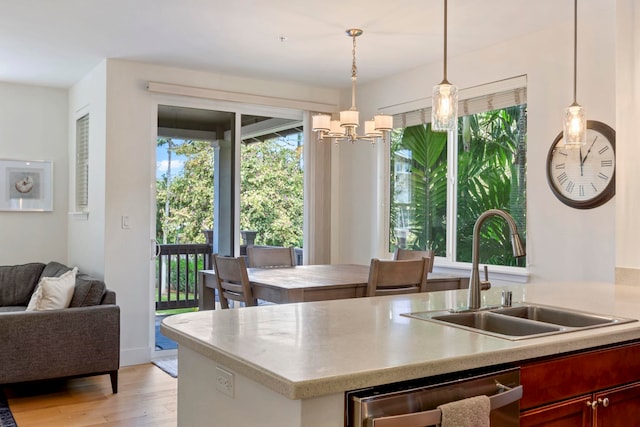 kitchen with open floor plan, a sink, light wood-style floors, pendant lighting, and stainless steel dishwasher