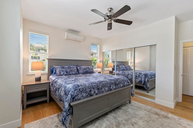 bedroom featuring light wood finished floors, a wall unit AC, a ceiling fan, and baseboards