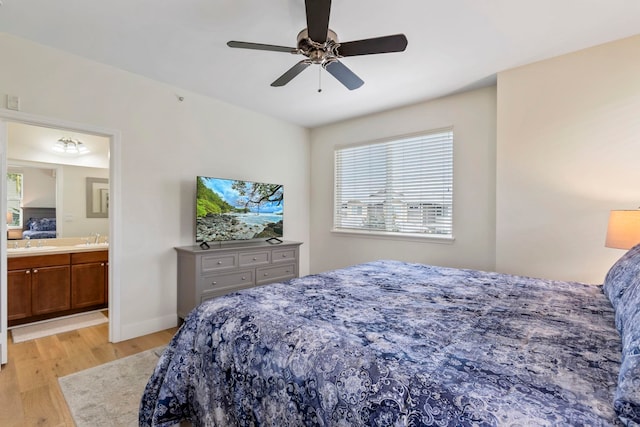 bedroom featuring ensuite bathroom, ceiling fan, light wood-style flooring, a sink, and baseboards