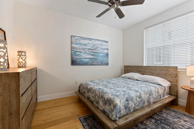 bedroom featuring ceiling fan, light wood-style flooring, and baseboards