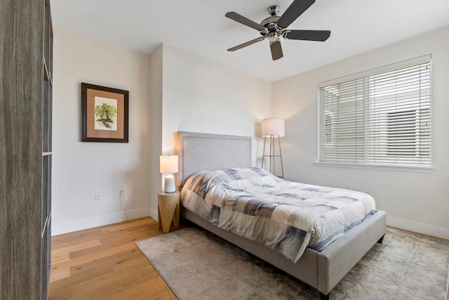 bedroom featuring ceiling fan, light wood-style flooring, and baseboards