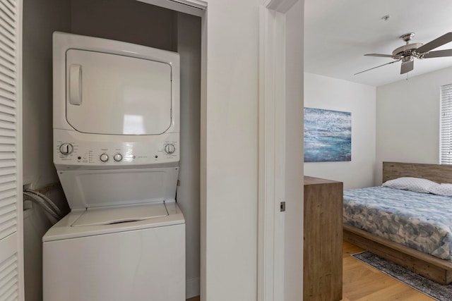 laundry area with ceiling fan, laundry area, light wood-type flooring, and stacked washer / drying machine