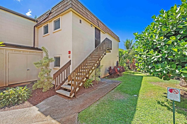 view of side of home with stairway, mansard roof, and a lawn