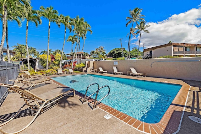 pool with a patio area and fence