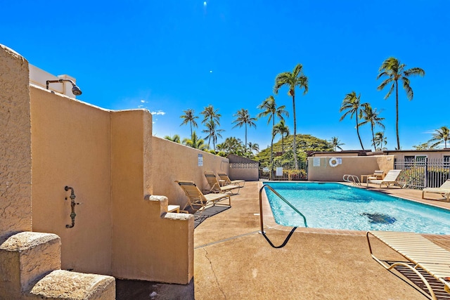 pool with a patio area and fence