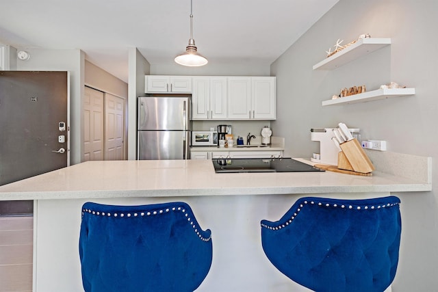 kitchen featuring a peninsula, pendant lighting, light countertops, and freestanding refrigerator