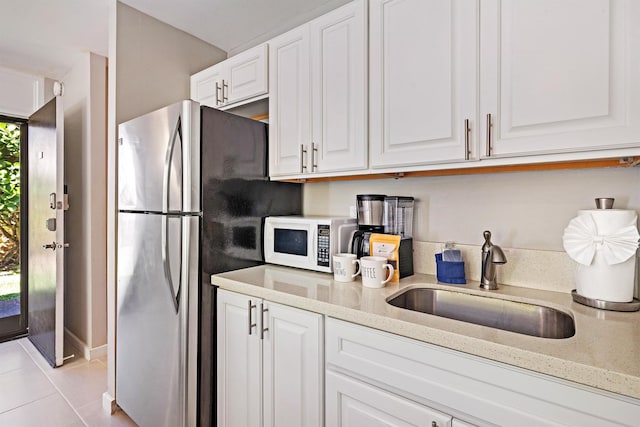 kitchen featuring white microwave, a sink, white cabinetry, and light stone countertops