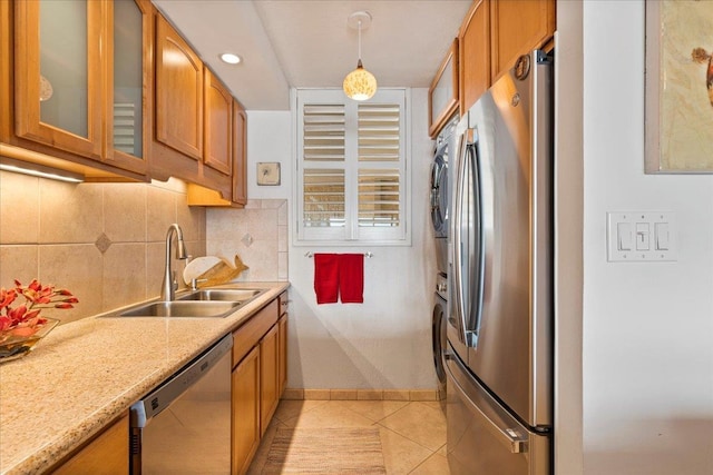 kitchen featuring pendant lighting, stainless steel appliances, light tile floors, light stone counters, and sink