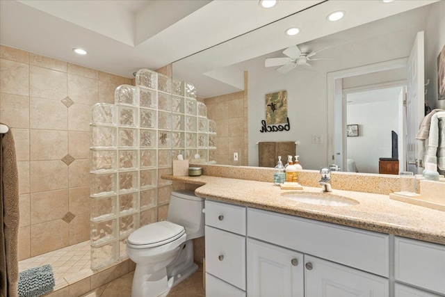 bathroom with oversized vanity, toilet, tiled shower, ceiling fan, and tile floors