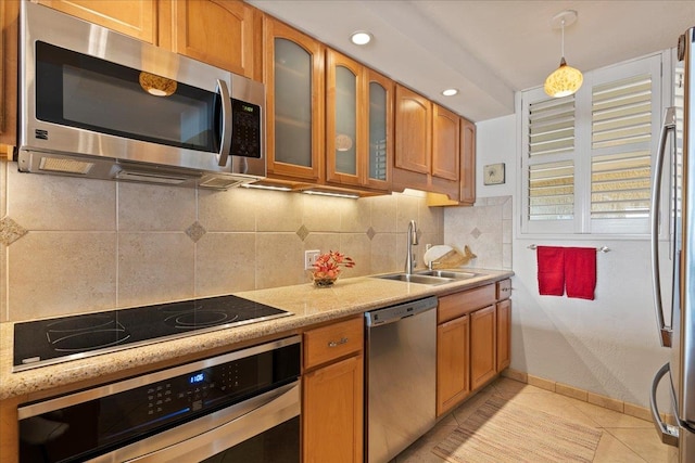 kitchen featuring backsplash, appliances with stainless steel finishes, sink, light tile floors, and pendant lighting