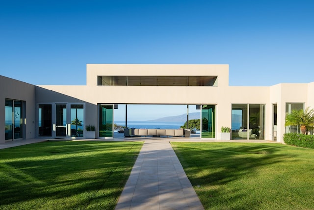 back of house featuring outdoor lounge area, a mountain view, and a lawn