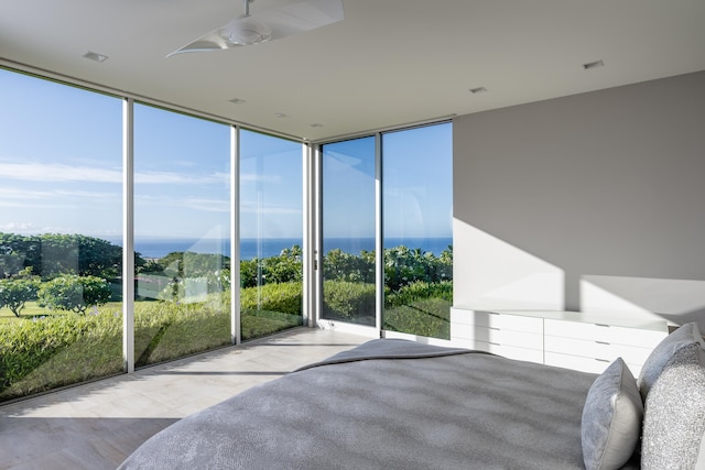 bedroom featuring ceiling fan, expansive windows, and a water view