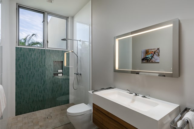 bathroom with tiled shower, vanity, and toilet