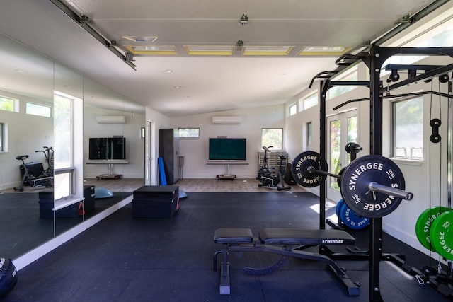 workout area with a wall mounted air conditioner, lofted ceiling, dark wood-type flooring, and a wealth of natural light